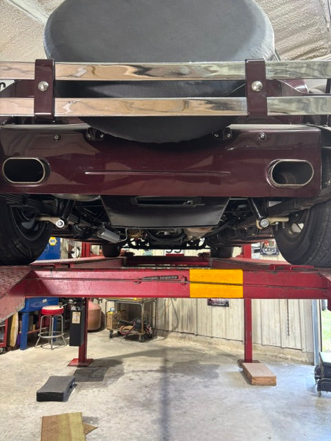 Rear underside on a lift - custom rollpan with dual exhaust exiting through it, rear-mounted spare tire